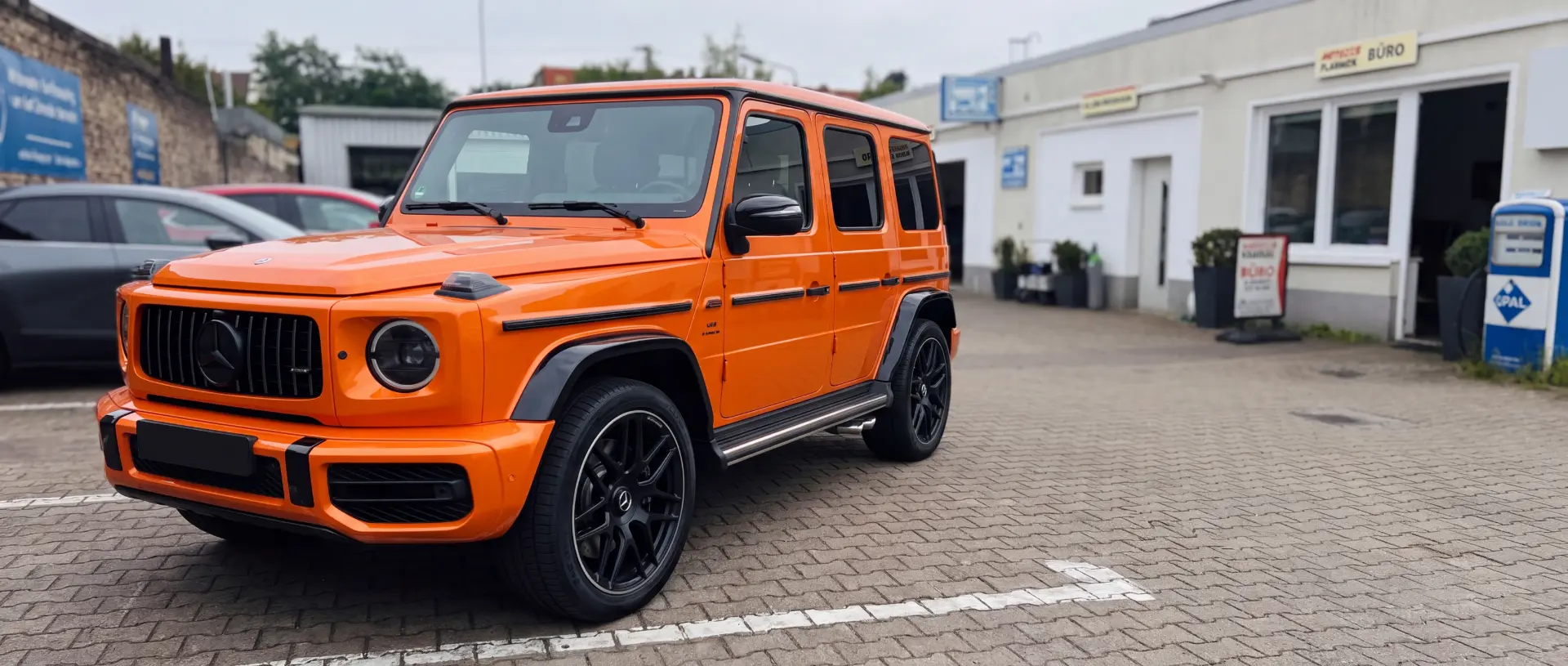 Orangefarbener Mercedes-AMG G 63 vor der Werkstatt bei der Wertermittlung