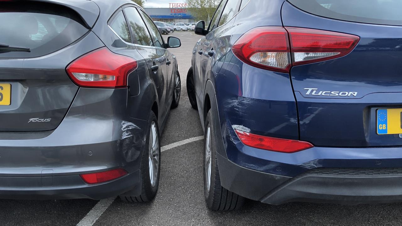 Zwei Fahrzeuge berühren sich nach einem Rückwärts-Zusammenstoß auf einem Supermarktparkplatz