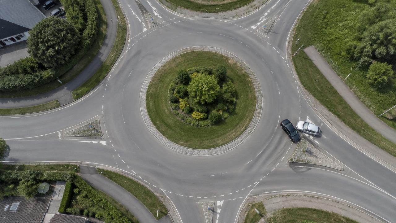 Luftaufnahme eines Kreisverkehrs mit zwei Fahrzeugen nach einer Kollision an der Ausfahrt